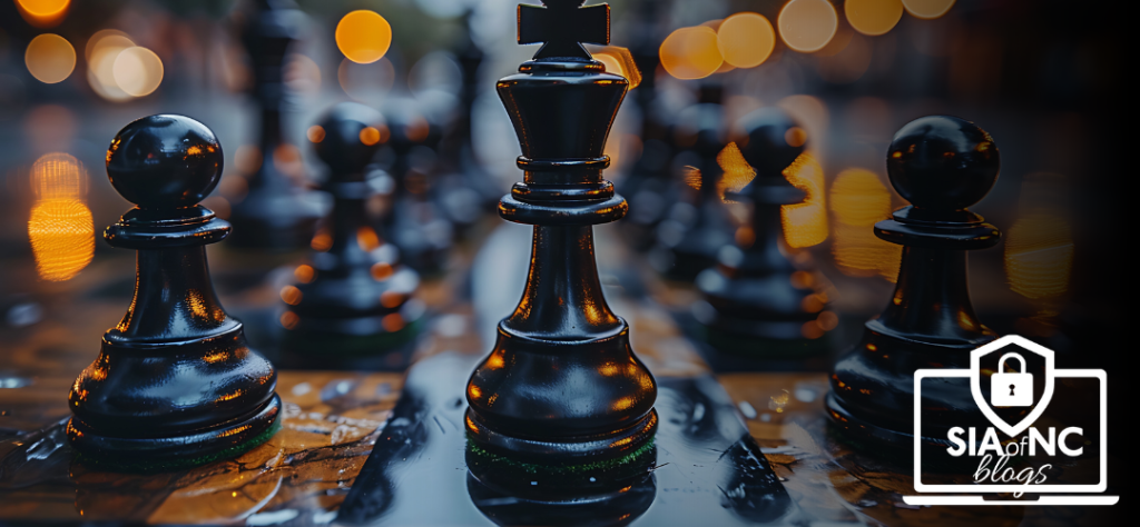 A close-up shot of a chessboard featuring polished black chess pieces, prominently displaying a black king piece at the center. The blurred background features soft bokeh lights, adding a warm and atmospheric feel to the scene.